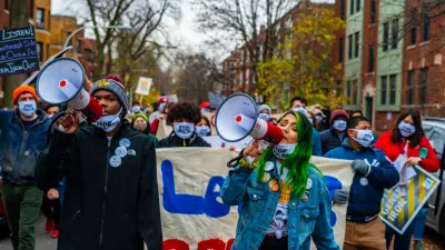 two people with bullhorns lead a group of marching protesters