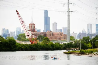 person kayaks down river with Chicago skyline in the distance