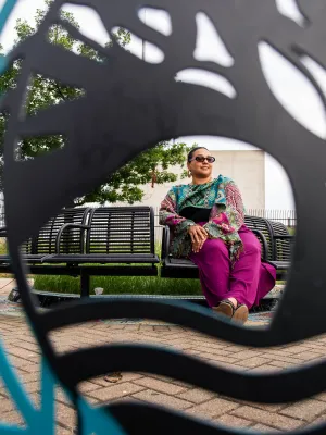 woman sitting on a bench visible through scultpure