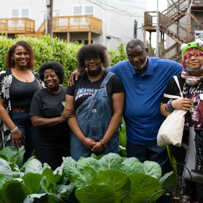 Five people in a neighborhood garden, posing for the camera.